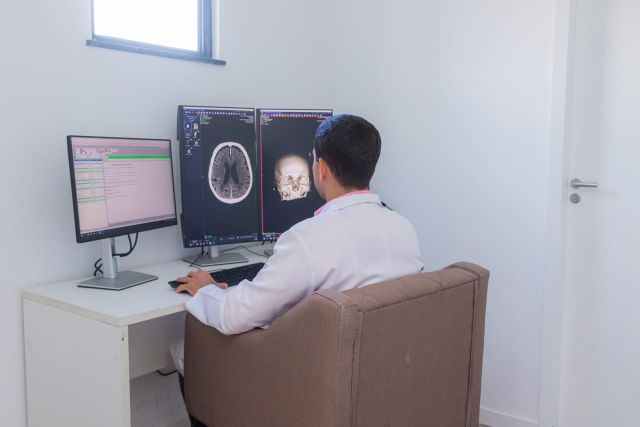 Médico avaliando exame de tomografia na sala de laudos